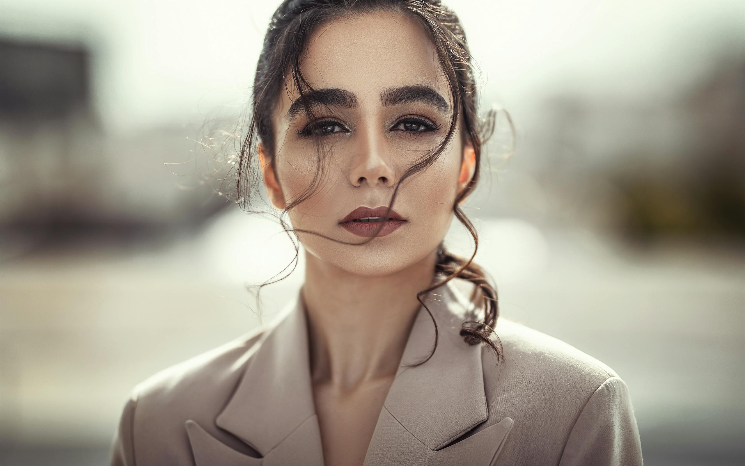 Stylish portrait of a woman with striking features, expressing confidence and elegance in an outdoor setting.