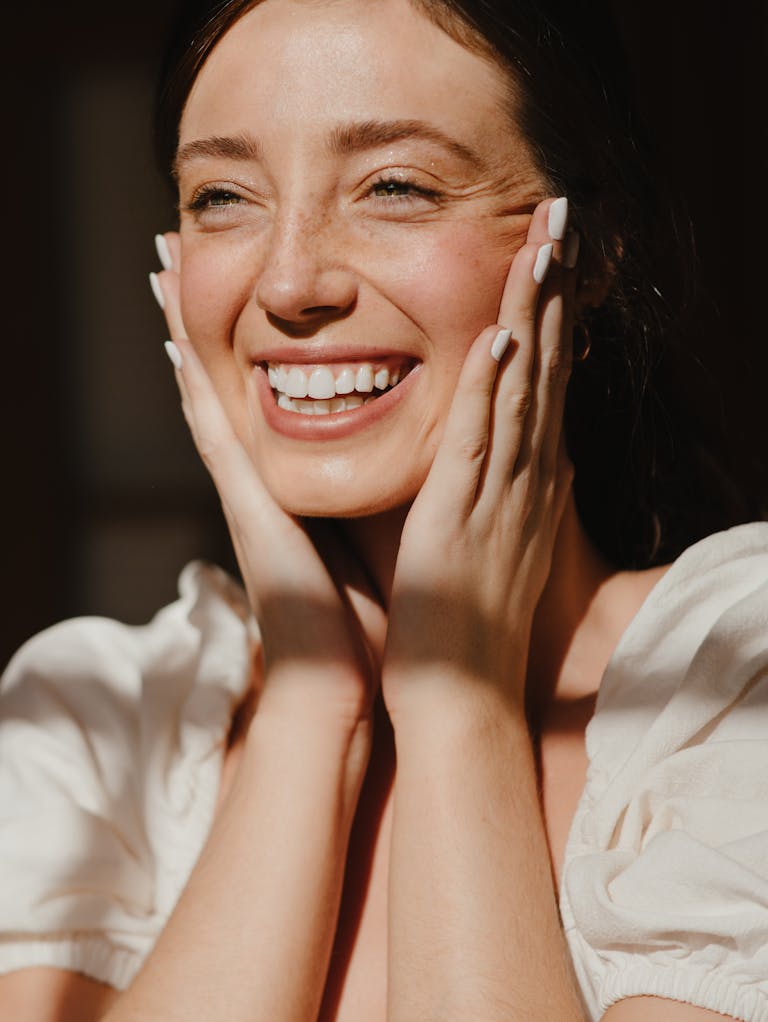 Close-up portrait of a joyful woman smiling brightly with natural lighting.